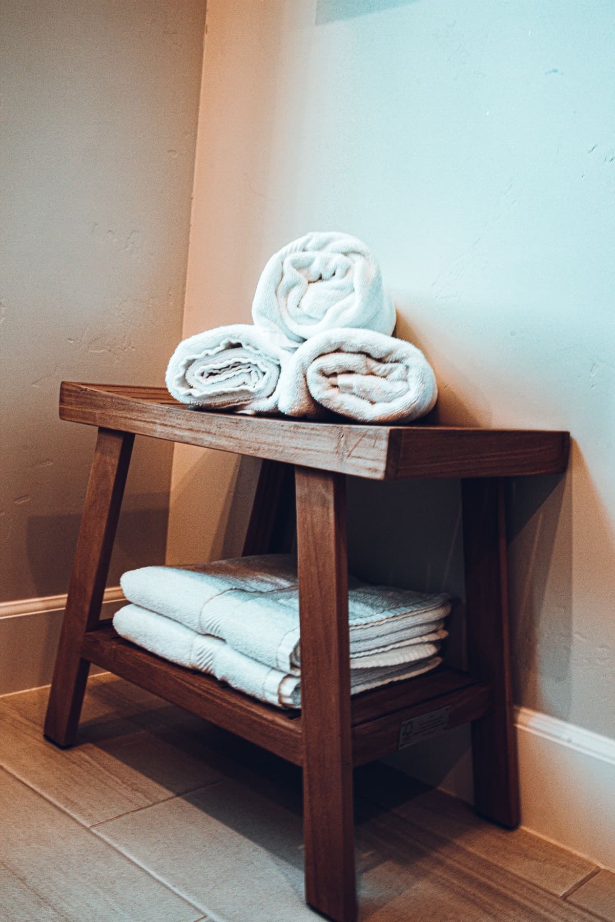 Rolled and folded white towels on a wooden bench.